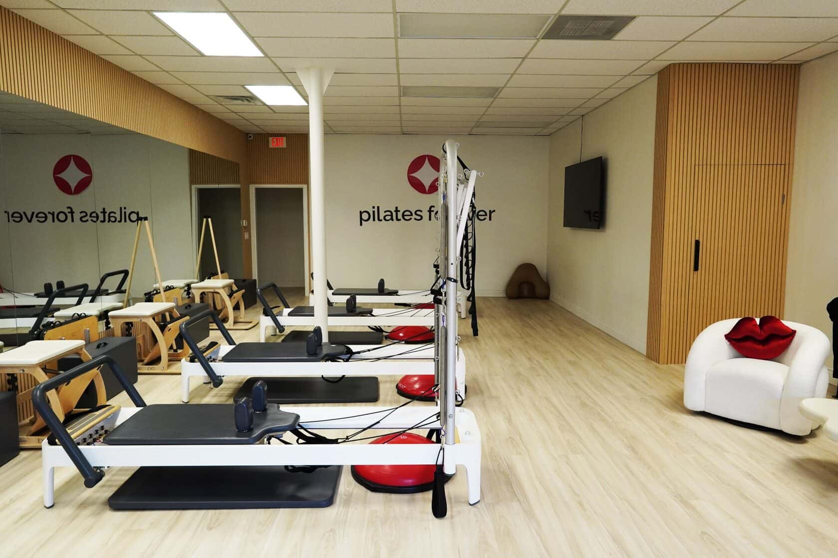 Wide view of Pilates Forever studio with reformers and lounge seating