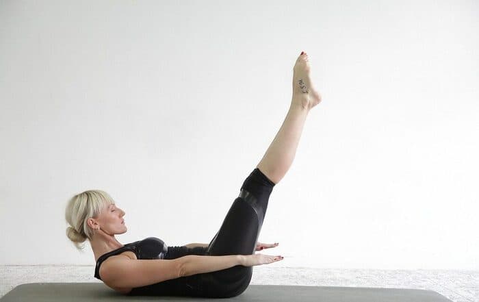 Side view of the Pilates Hundreds core exercise on a mat